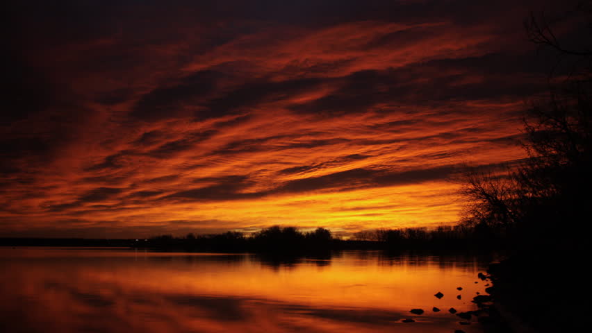 Awe-inspiring view of a multi-colored sunrise over a lake in Colorado. Dark sky