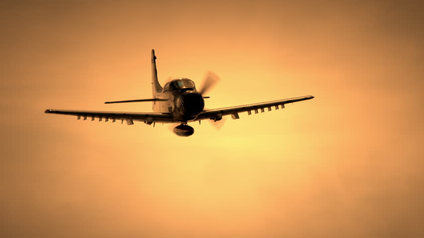 WWII propeller fighter plane flying towards camera against golden sky in slow motion