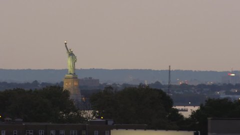 NEW YORK - AUGUST 8, 2014: Statue of Liberty and MTA subway train on elevated track at sunset in 4K in New York. NYC subway is a rapid transit system leased to the New York City Transit Authority.