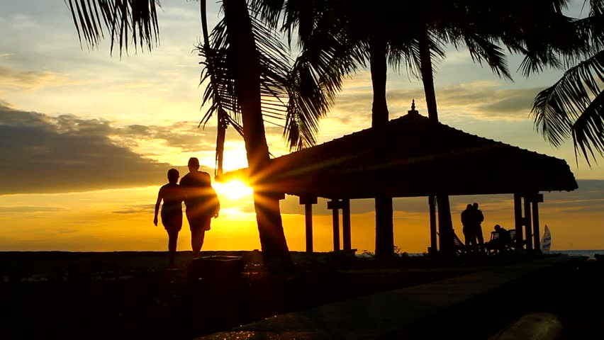 People walking at sunset, next to water house 