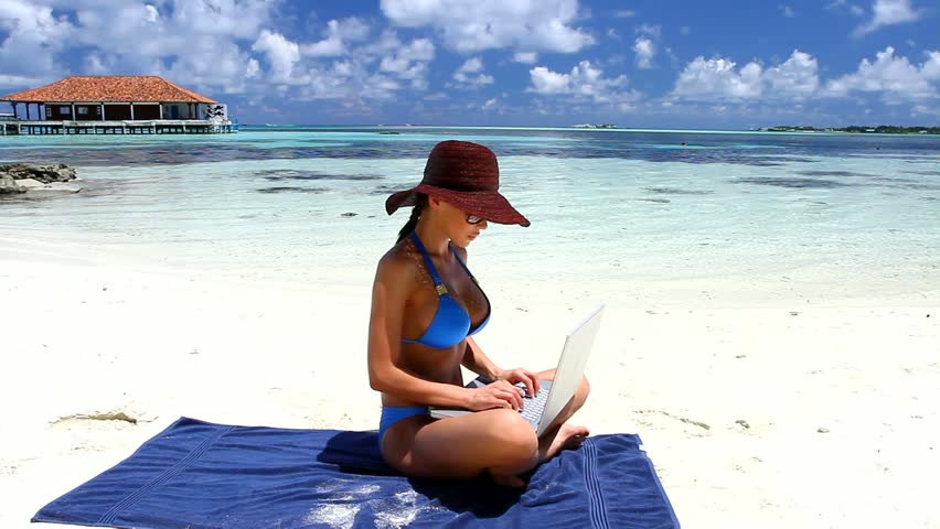 Beautiful woman working on laptop near water at Maldives 