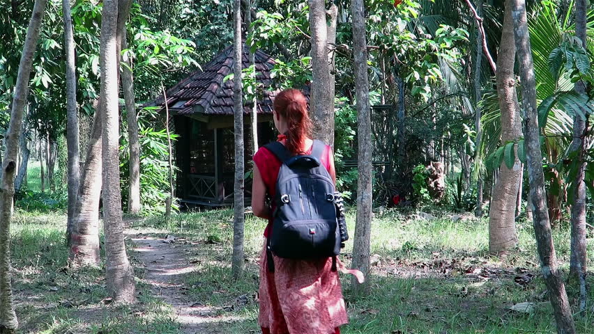 Girl with backpack walking on a path through tall palm trees in Ubud, Bali