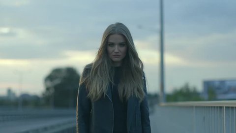 Young beautiful woman in a leather jacket standing in a middle of a street 