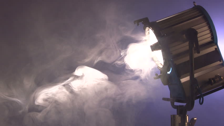 White spot light turns to camera through smokey club