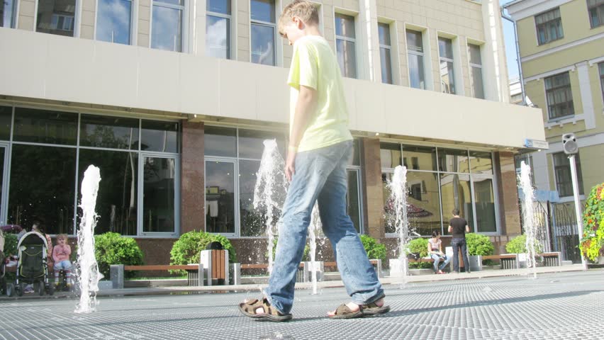 Mother with kids go to the fountain and feet trying to catch the water jet, time lapse