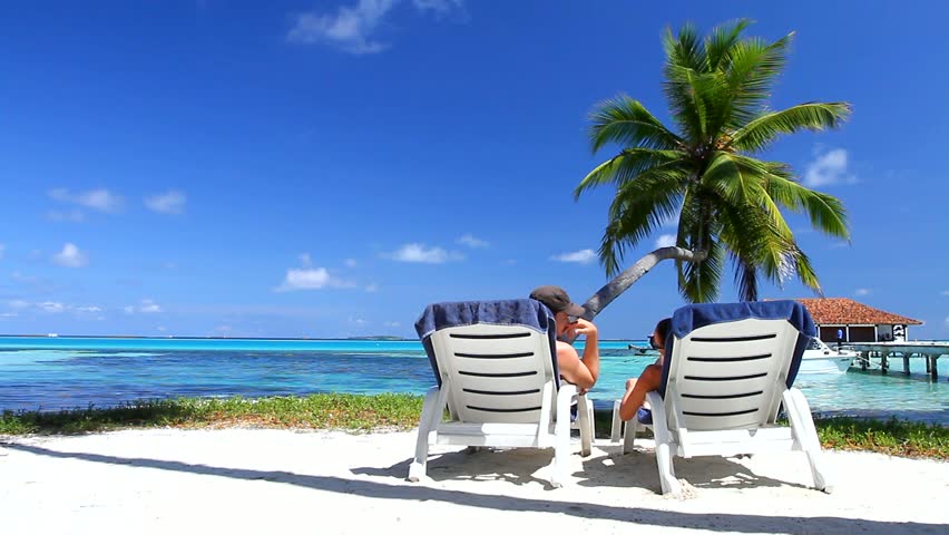 Romantic couple resting on sunbed at Maldives seaside 