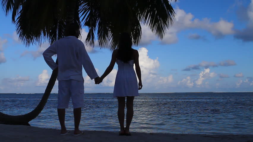 Romantic couple standing next to palm tree 