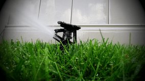 Oscillating lawn sprinkler watering grass in backyard - Garden automatic irrigation system watering lawn