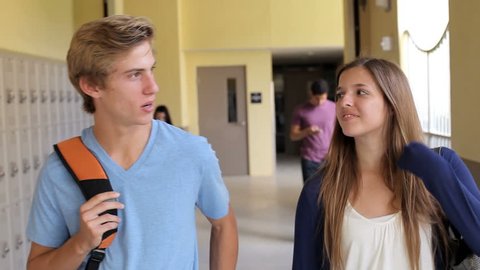 High School Student Couple Walking Along Hallway