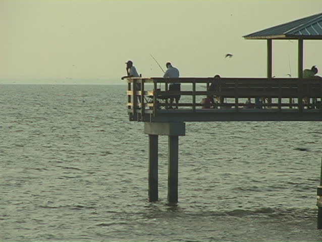 Static shot of a fishing pier in Mobile Bay - sunset in background