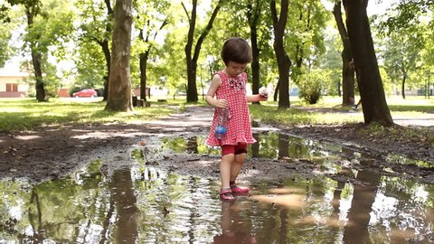 little girl playing in the puddle of mud