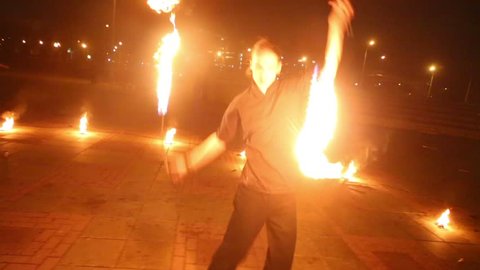 Boy shows different kinds of burning pois rotation at evening fire show.