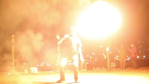 Young man makes fireballs, standing at one place and turning around himself.