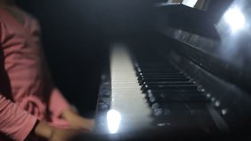 The child learns to play the piano. Video with sound. Close up.