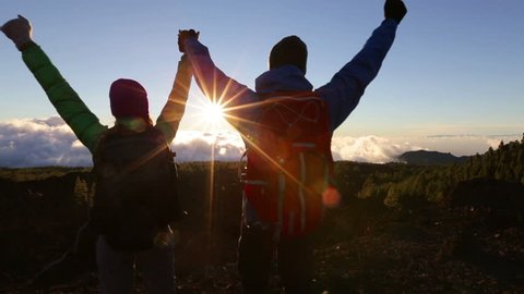 Success, achievement and accomplishment concept with hiking people cheering jumping, running and celebrating of joy on trekking hike outside. Hikers having fun at sunset.