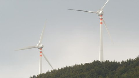 Wind turbine in woody hill rotating and producing clean energy