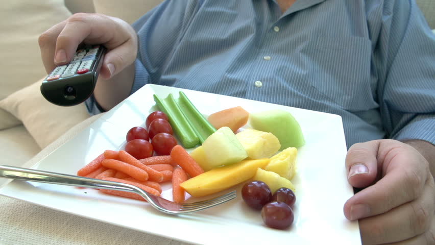 Overweight Man Eating Healthy Meal Sitting On Sofa