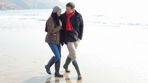 Young Couple Walking Along Winter Beach