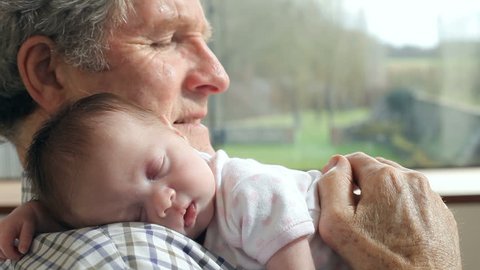 Grandfather Holding Sleeping Newborn Baby Granddaughter