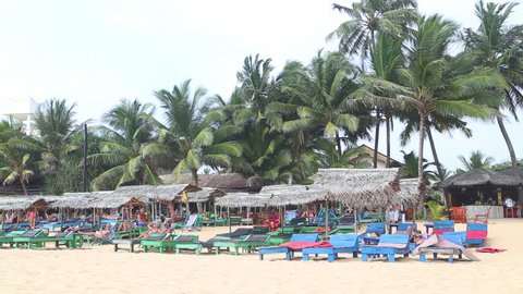 HIKKADUWA, SRI LANKA - FEBRUARY 2014: View of Hikkaduwa beach bar while wind is blowing and palms are swaying in the wind. Hikkaduwa is famous for its beautiful beaches.