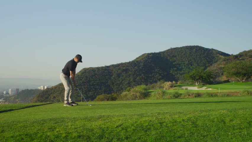 A golfer takes a swing on a golf course.