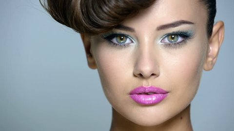 Closeup face of a beautiful  girl with blue eye makeup and pink lips. Full hd video clip.