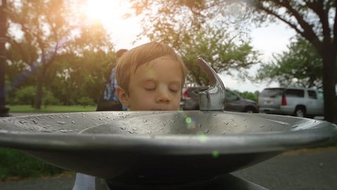 Funny Stock video clip of little boy trying to drink from a water fountain. HD Slow motion