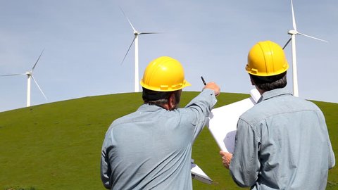 Two engineers working near wind powered generators.