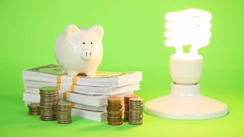 Stop motion effect of money pile growing after compact fluorescent light bulb is turned on.