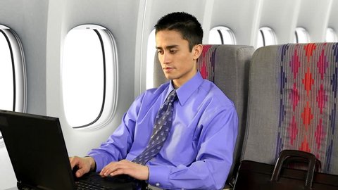 Businessman on a commercial airplane using a notebook computer.