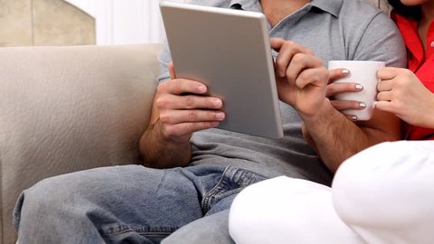 Young couple using a tablet computer at home. Camera pans from waist level (tablet) up to their faces.