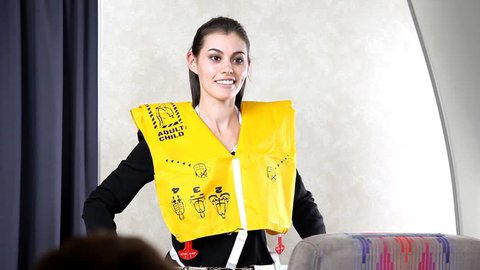 Airline flight attendant demonstrating a life vest before takeoff.