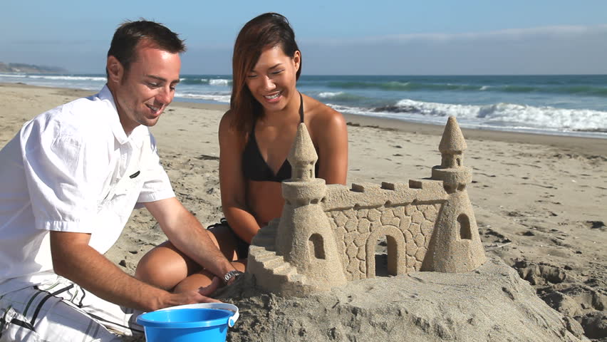 young couple building sandcastle together on Stock Footage Video (100% ...