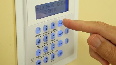 Close up of a security alarm keypad with person arming the system.