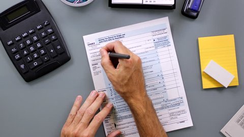 Time-lapse of man filling out a United State 1040EZ income tax form. Names and info are ficticious.