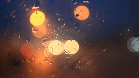 rain flows and wipers on the front windshield glass window of car stopping beside the road with beautiful colorful blurry light of traffic outside on the road, broken heart, sad, cry scene