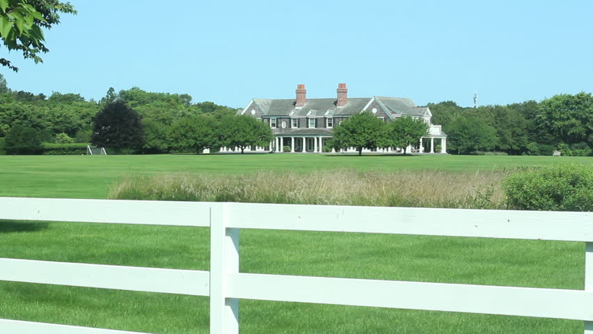 Establishing shot of mansion behind a white picket fence in East Hampton, NY. 1080p HD with natural sound.
