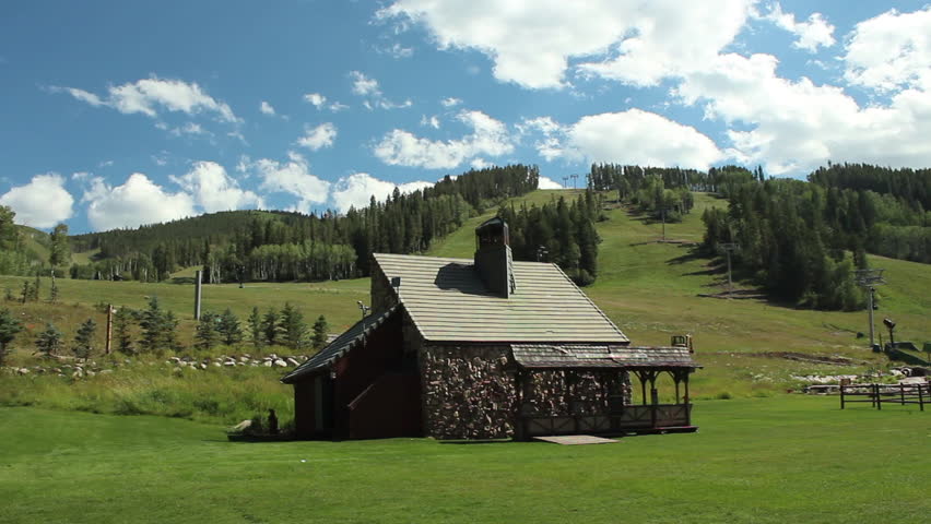Wide beauty shot of a small stone building in Beaver Creek, Colorado. Hillside with blue sky 1080p HD.
