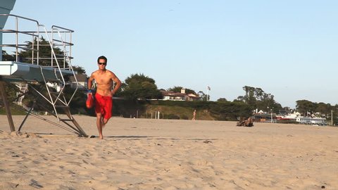 Male lifeguard running to help an swimmer in distress.