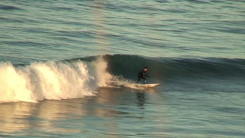 A surfer rides up and down a wave and performs turns in cold water
