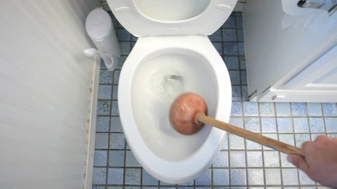 Using plunger for clogged toilet in bathroom