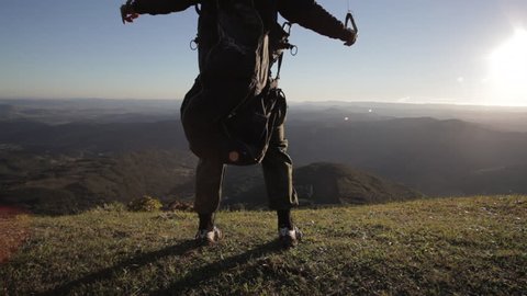 Man launching with paraglider from mountain top at sunrise. Freedom concept