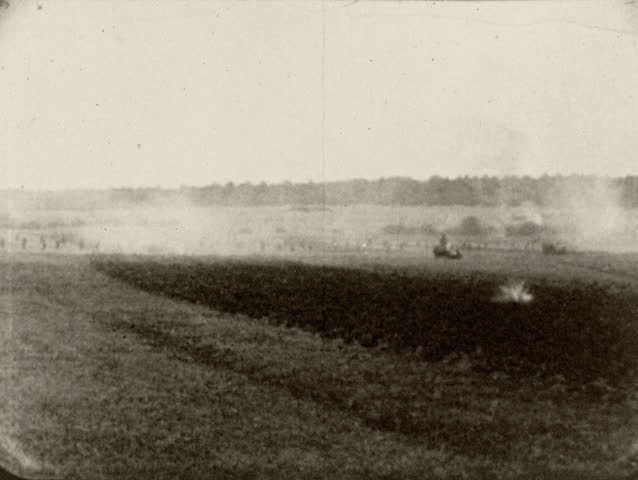Europe - World War I - 1914-1918. Tank fires and climbs embankment as infantry fights in the background of a battlefield