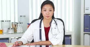 Chinese doctor talking to camera at desk