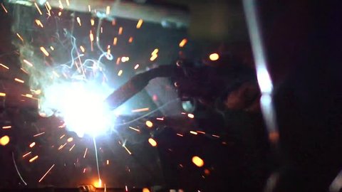 Welding. Welder worker welding metal by electrode with bright electric arc and sparks during manufacture of metal equipment. Full HD 1920x1080p footage, High speed camera shot 240 fps, Slow motion
