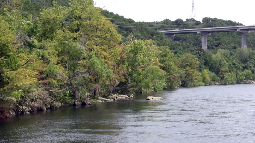 Video Pan right of the Mansfield Dam on the Colorado River near Austin Texas. Concrete spillway, earthen dam with high vehicle bridge crossing the river. 