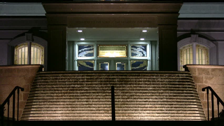 Video of the Mormon or LDS Temple in San Antonio Texas at night. Bright lights with colorful accents. Waterfall garden in front with golden angel Moroni statue on top of steeple. 