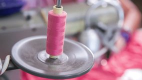 Sewing machine picking thread from sheath in slow motion close up. Slow motion footage of tailor working on a pink dress, sewing on a sewing machine in studio.