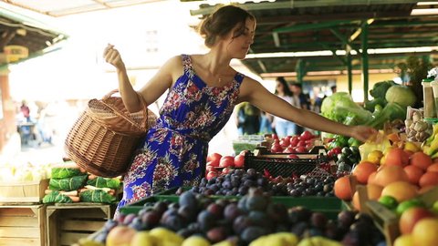 Woman putting tomatoes and peaches to the basket on the market
