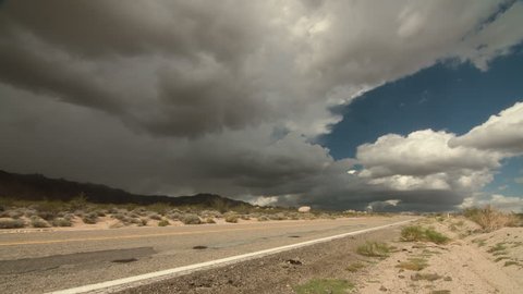 Time lapse storm clouds travel over an old road in the Mojave Desert, California, USA.